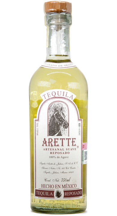 Arette Artesanal Suave Reposado tequila bottle displayed on a wooden table, surrounded by agave plants and warm lighting to highlight its golden color and artisanal craftsmanship.