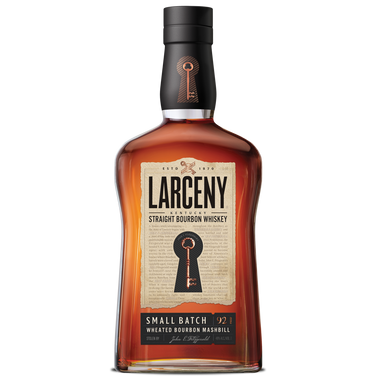 Bottle of Larceny Small Batch Bourbon Whiskey with a rich amber color, placed on a wooden surface, surrounded by bourbon glasses and a warm, rustic background.