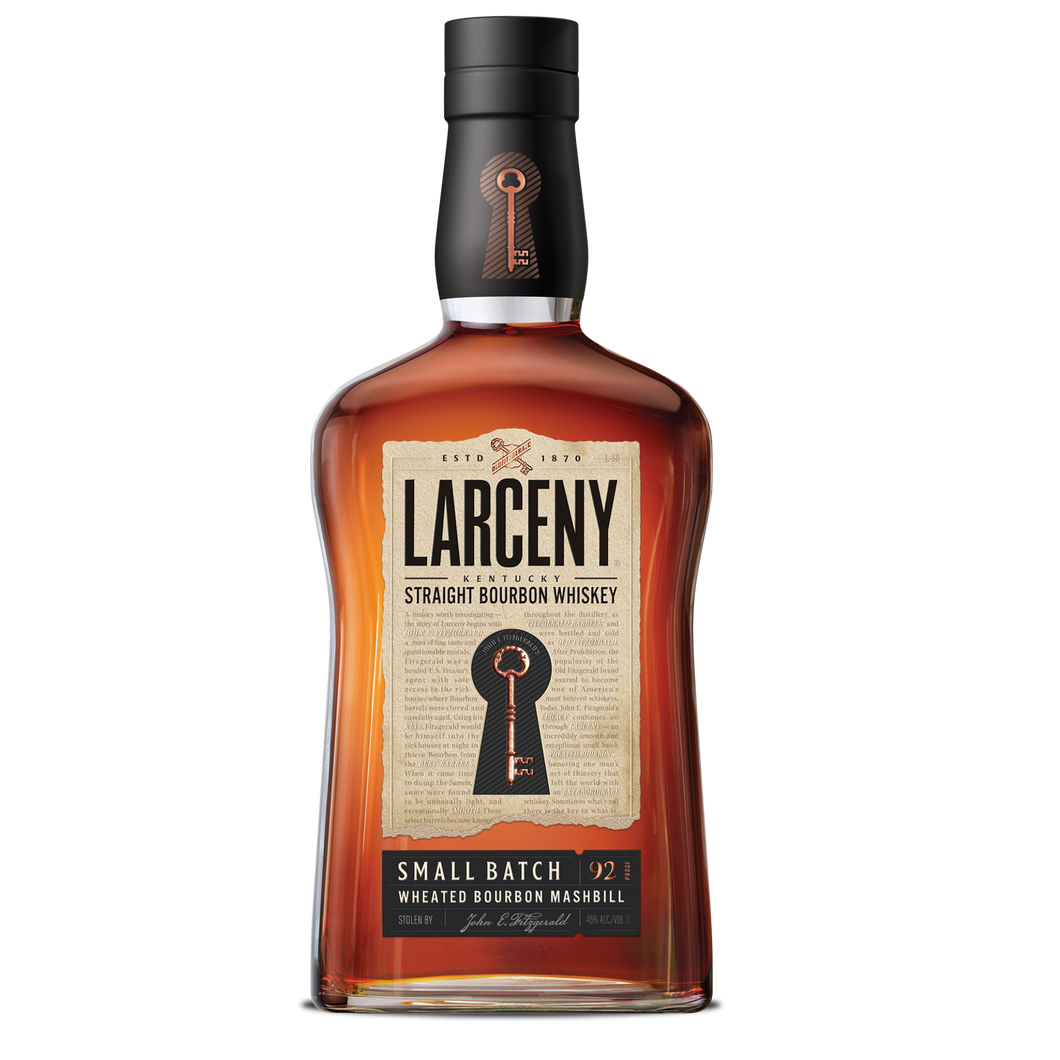 Bottle of Larceny Small Batch Bourbon Whiskey with a rich amber color, placed on a wooden surface, surrounded by bourbon glasses and a warm, rustic background.